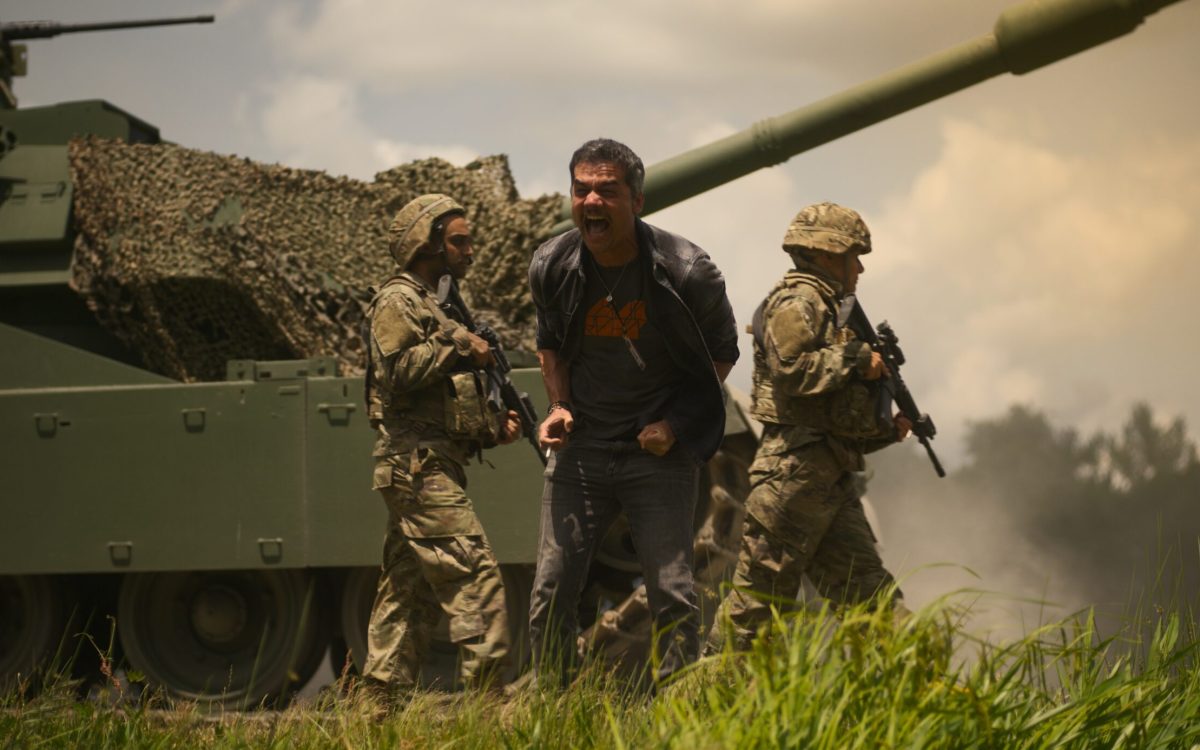 Cena de 'Guerra Civil' co mWagner Moura atrás de um tanque de guerra com soldados